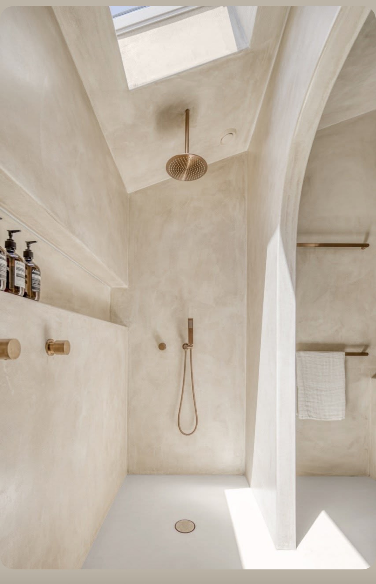 Sculpted luxury shower with skylight, curved walls and brushed brass fittings