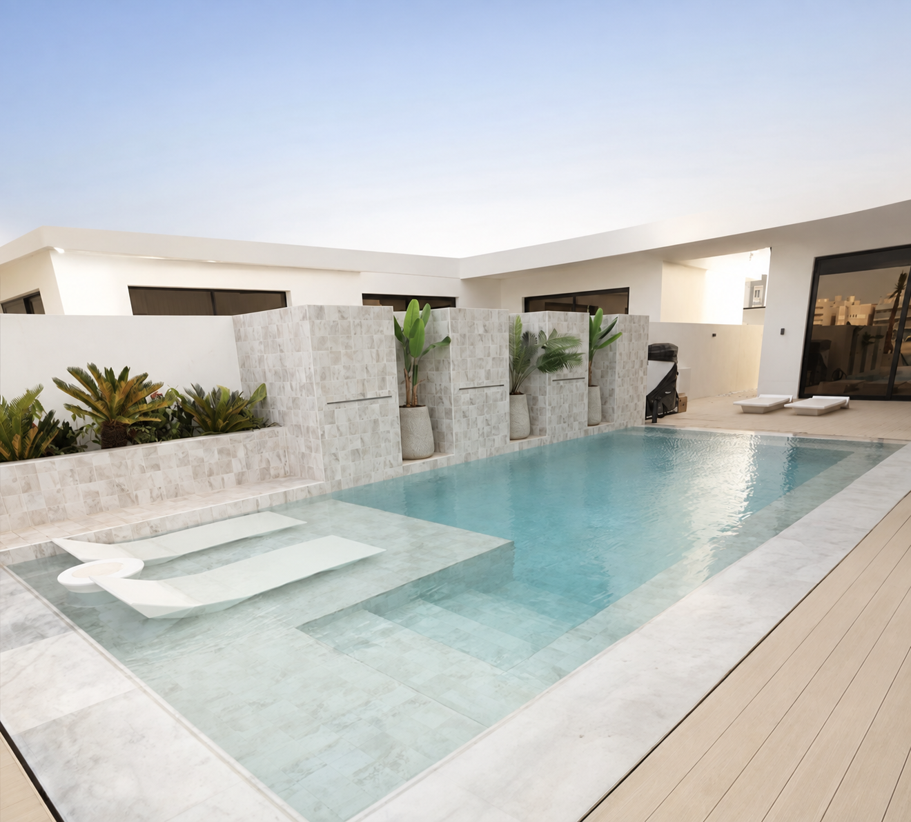 Contemporary luxury pool with submerged loungers and stone water features