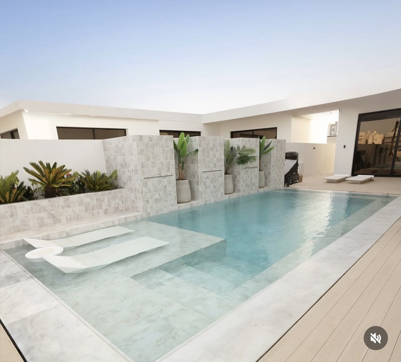 Contemporary luxury pool with submerged loungers and stone water features
